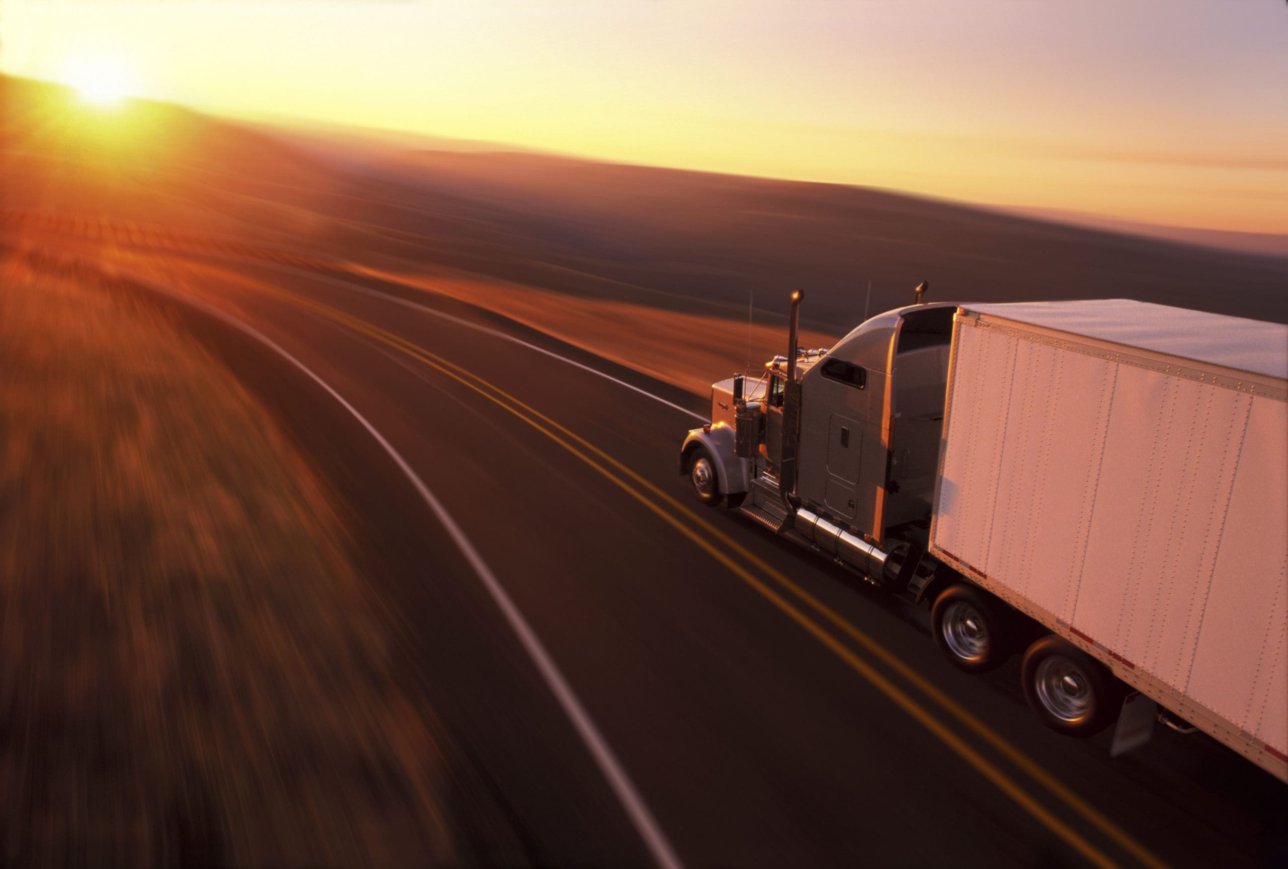A transport truck driving under a sunset